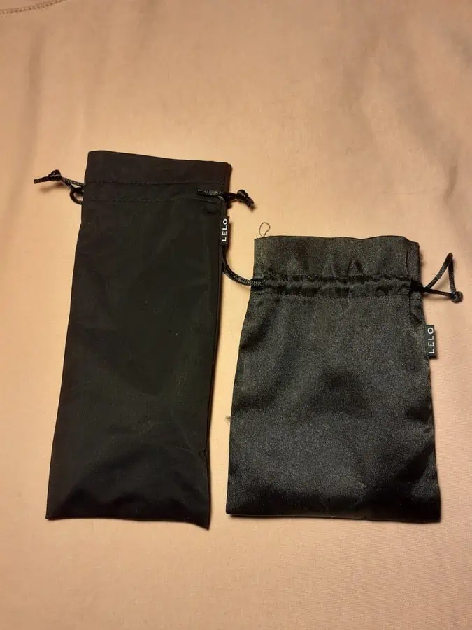 Porównanie woreczków masażerów LELO Dot i LELO Sona. Większy woreczek Dota jest zrobiony z elastycznego materiału, mniejszy Sony z satyny.